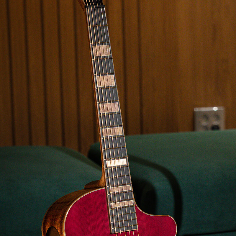 Cort Modern Burst guitar highlighting its fretboard leaning on a couch