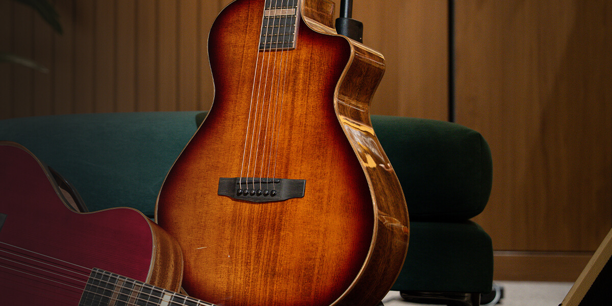 Cort Modern Burgundy guitar laying on a carpet beside a standing Cort Modern Burst guitar